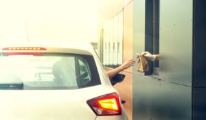 worker serving fast food drive thru