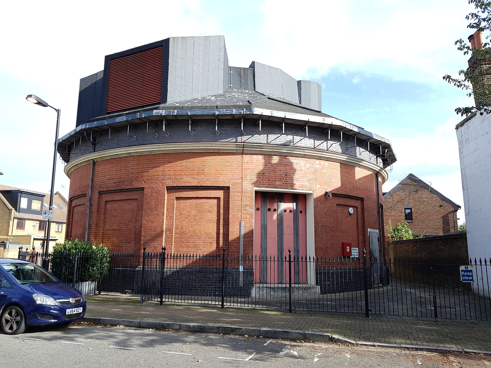 Round red-brick ventilation station building with a grey louvred plant structure on the roof