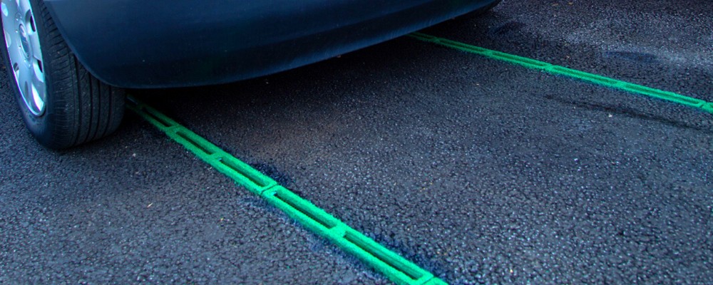 A car parked over green Roadvent slot drains set into the road surface
